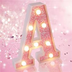 an illuminated light up letter on a pink and white background with sparkling lights around it