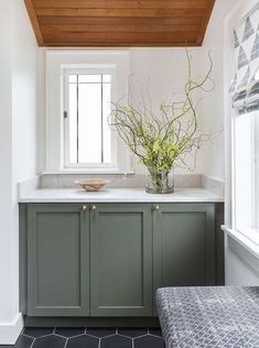 a kitchen with green cabinets and white counter tops