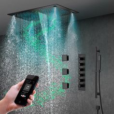 a hand holding a cell phone in front of a shower head with green water coming from it