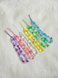 six different colored beads are lined up on a white surface, with one bead in the shape of a christmas tree