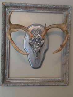 a deer's head mounted on the wall in a silver frame with crystal beads