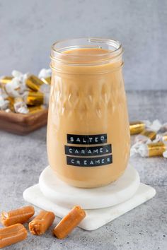 a glass jar filled with caramel creamer next to some candy