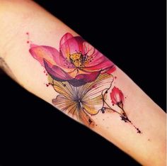 a watercolor style flower tattoo on the arm