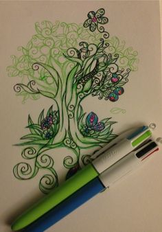 a green pen sitting on top of a white paper next to a drawing of a tree