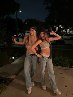 two young women standing next to each other in front of a building at night time