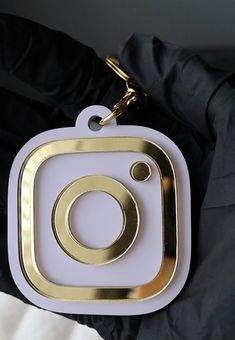 a white and gold camera keychain hanging from a black jacket