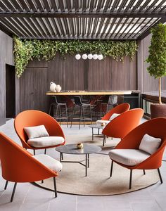 an outdoor living area with orange chairs and tables