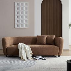 a brown couch sitting on top of a hard wood floor next to a white rug