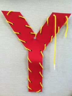 the letter y is made out of red paper with yellow thread and beads on it