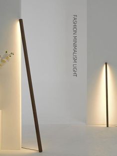 two tall wooden poles with flowers in them on the floor next to each other and one light that is turned on