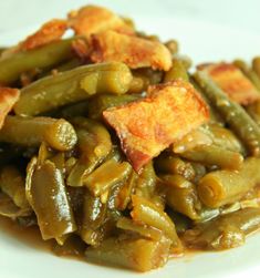 green beans and bacon are served on a white plate with croutons in the middle