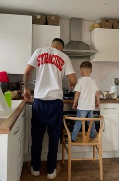 a man standing next to a little boy in a kitchen