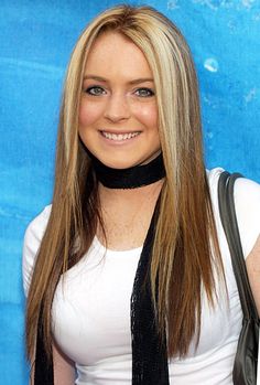 a woman with long blonde hair wearing a white shirt and black neck tie smiling at the camera