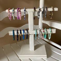 several bracelets are hanging from a white rack on a shelf in the corner of a room