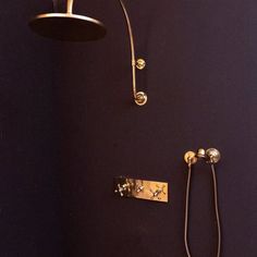 a shower head and hand shower in a bathroom with purple walls, brass fixtures and black tile flooring