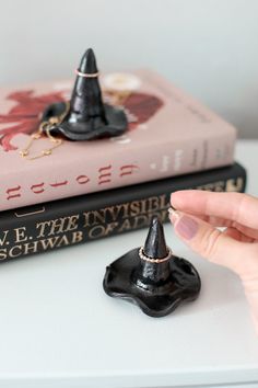 a hand is pointing at a tiny black hat on top of two bookends