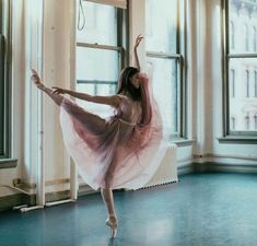 a ballerina in a pink tutu is posing for the camera with her arms stretched out