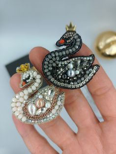 Elevate your style with these exquisite handmade swan brooches. Crafted with meticulous attention to detail, one swan showcases a pristine white hue, while the other exudes elegance in deep black. 🖤⚪ Adorned with delicate crowns, these brooches offer a touch of regal charm to complement your look. Perfect to enhance your style and make a statement, these brooches exude sophistication and beauty. Choose your preferred color or indulge in both for a versatile accessory collection. ✨💖 📏Dimension  Length: 4 cm  Width: 4.7 cm 🎁Delight in Every Box: Your Special Gift Awaits! Welcome to a world where elegance and craftsmanship merge in perfect harmony! With great pleasure, I present to you our meticulously designed wearable art, a true epitome of beauty and style. 🪡 Every piece is a labor of Swan Brooch, Collar Pins, White Swan, Crystal Headband, Art Accessories, Black Swan, Lapel Pins, Wearable Art, Brooch Pin