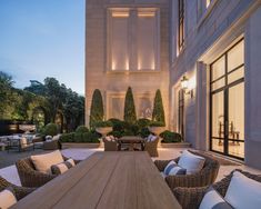 an outdoor dining area with wicker chairs and wooden table surrounded by potted plants