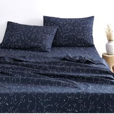 a bed with blue sheets and white stars on the sheet set is next to a plant