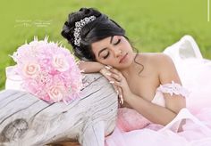 a woman in a wedding dress laying on a log