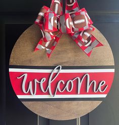 a welcome sign with footballs on it and a bow hanging from the front door