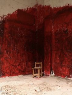 a chair sitting in an empty room with red paint on the walls and flooring