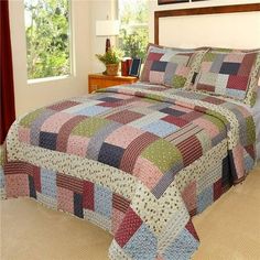 a bed in a bedroom with a colorful quilt on the comforter and pillow cases