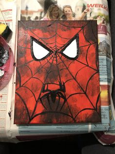 an image of a spiderman face painted on a piece of paper with paintbrushes