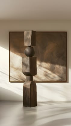 a wooden sculpture sitting on top of a white floor next to a framed art piece