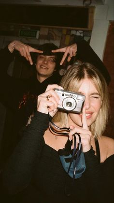 a woman taking a photo with her camera while another man looks at her in the background