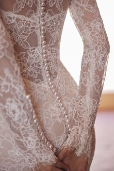 the back of a woman's dress with lace and pearls on her body, in front of a white background