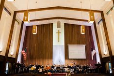 an orchestra performing in front of a large screen with american flags hanging from the ceiling