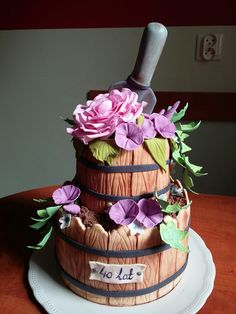 there is a cake that has flowers on the top and wine bottle in the middle