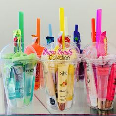 three plastic cups filled with different types of toothbrushes and gels on top of a table