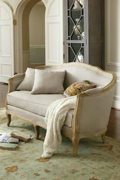 a white couch sitting on top of a wooden floor next to a rug covered in pillows