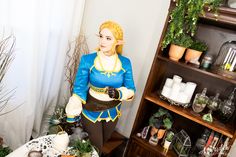 a woman dressed as zelda stands in front of a table with potted plants