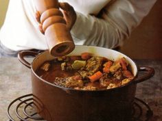 a person pouring some food into a pot