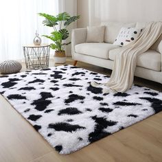 a living room with a white couch and black and white area rug on the floor