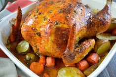 a roasted chicken with carrots and potatoes in a casserole dish