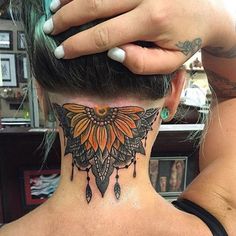 a woman's neck tattoo with an orange butterfly and feathers on the back of her head