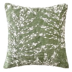 a green and white pillow with an abstract design on the front, featuring small leaves