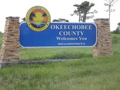 a welcome sign for okeechobee county in front of some trees and grass