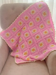 a pink crocheted blanket sitting on top of a chair