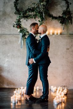 two men standing next to each other in front of candles