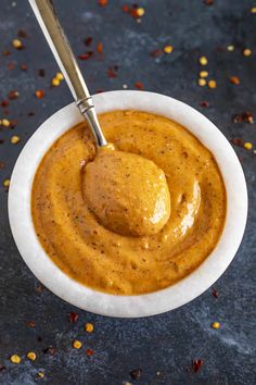 a spoon in a small white bowl filled with peanut butter and chili flakes on a dark surface