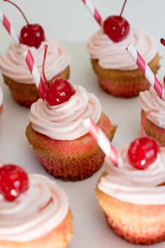 cupcakes with white frosting and cherries on top are arranged in rows