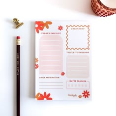 a notepad and pencil on top of a white table with a flowered design