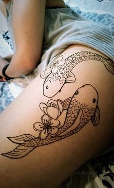 a woman laying on top of a bed next to a fish and flower tattoo design