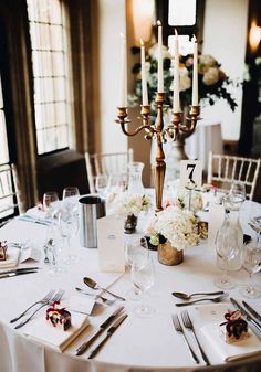 the table is set with silverware and white flowers